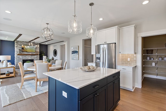 kitchen featuring light hardwood / wood-style floors, white cabinetry, stainless steel fridge with ice dispenser, and a fireplace