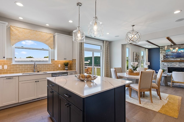 kitchen featuring sink, plenty of natural light, pendant lighting, light hardwood / wood-style floors, and white cabinets