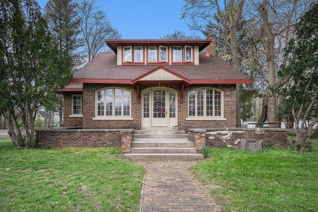 633 Marshall St, Allegan, MI 49010 - view of front facade featuring a chimney, a front yard, and brick siding