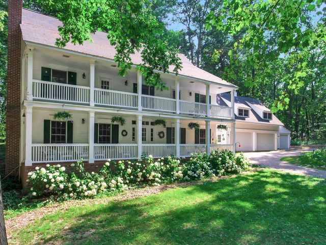 view of front facade featuring a porch, a garage, a balcony, and a front yard