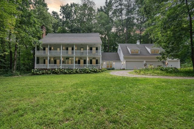 view of front of house with a porch, a balcony, and a yard