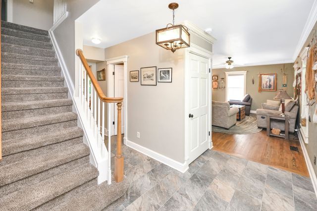 stairway with ceiling fan, crown molding, and wood-type flooring