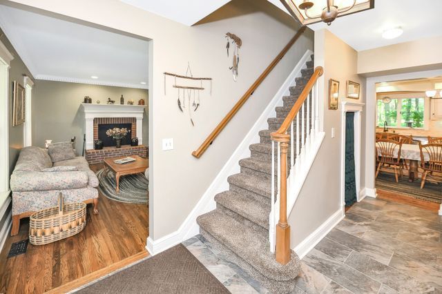 stairs with a chandelier, hardwood / wood-style flooring, and a brick fireplace