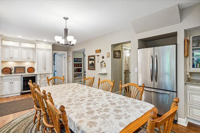 dining room with dark hardwood / wood-style flooring, wine cooler, and a chandelier