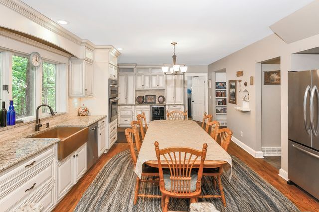 kitchen with sink, an inviting chandelier, light stone counters, pendant lighting, and appliances with stainless steel finishes