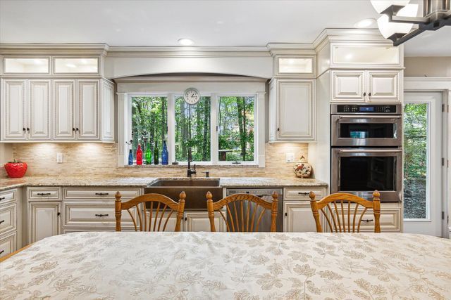 kitchen featuring a notable chandelier, decorative backsplash, light stone counters, and stainless steel appliances