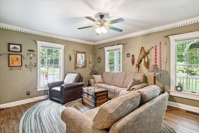 living room with ceiling fan, a healthy amount of sunlight, crown molding, and dark wood-type flooring