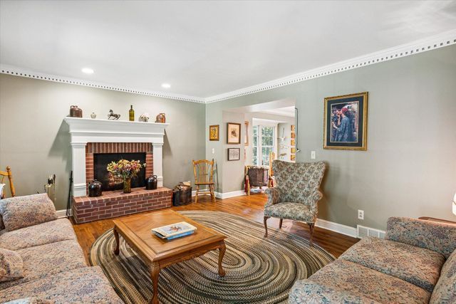 living room featuring hardwood / wood-style flooring, a brick fireplace, and crown molding