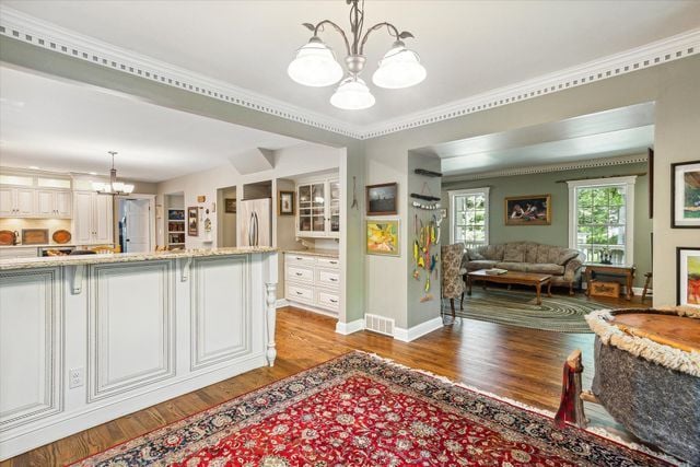 kitchen featuring a chandelier, pendant lighting, light wood-type flooring, and stainless steel refrigerator