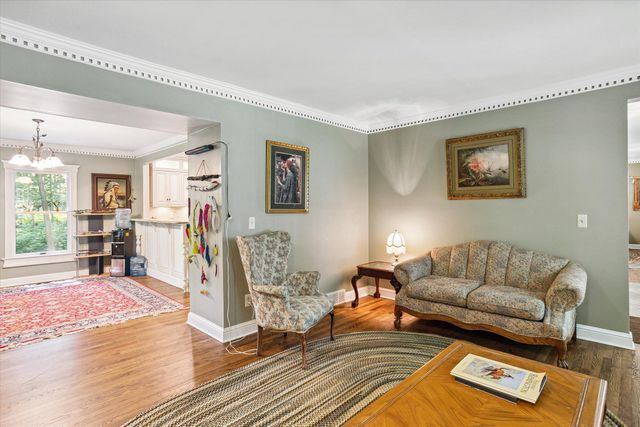 living room with a chandelier, wood-type flooring, and ornamental molding