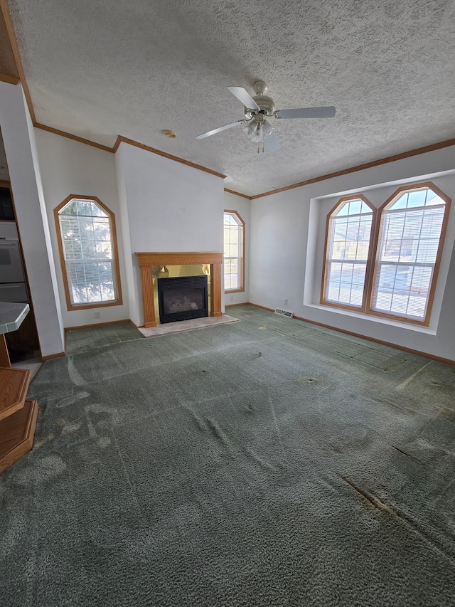 unfurnished living room featuring a textured ceiling, ceiling fan, carpet flooring, and ornamental molding