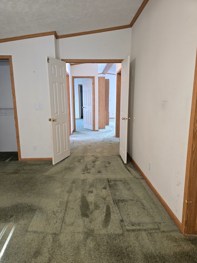 corridor with a textured ceiling, carpet flooring, and ornamental molding