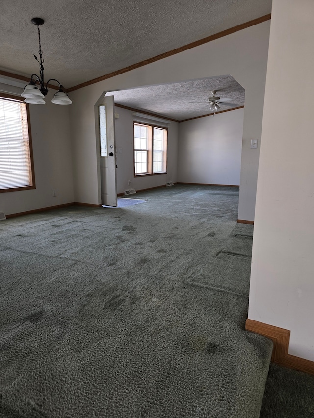 carpeted empty room featuring ceiling fan with notable chandelier, a textured ceiling, and crown molding