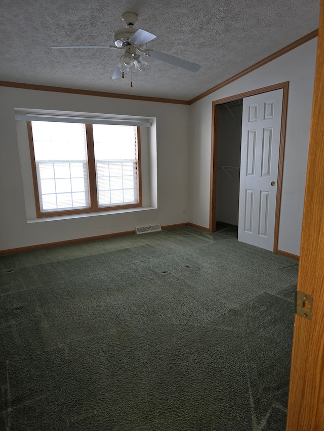 empty room featuring a textured ceiling, ceiling fan, carpet flooring, and ornamental molding