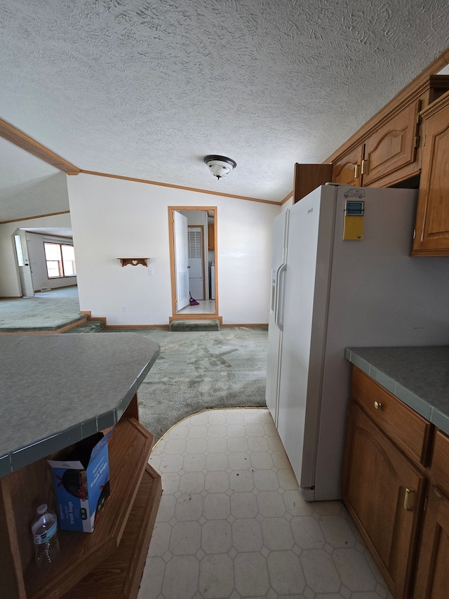 kitchen with a textured ceiling, ornamental molding, and white refrigerator with ice dispenser