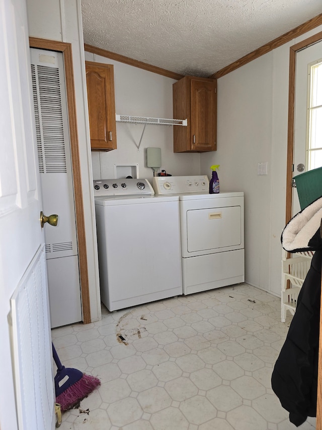 laundry area with a textured ceiling, crown molding, washing machine and clothes dryer, and cabinets