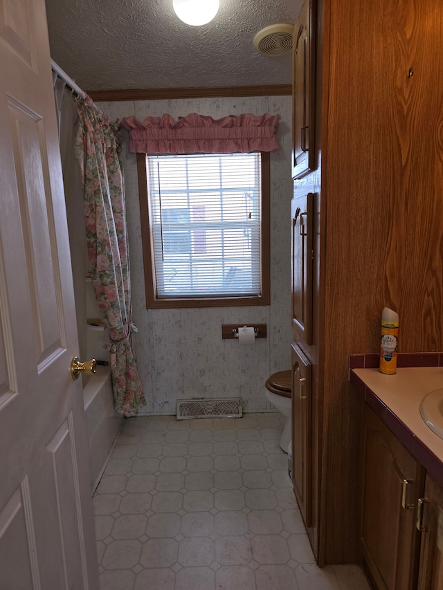 full bathroom with a textured ceiling, vanity, shower / tub combo, toilet, and ornamental molding