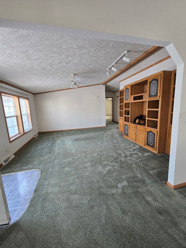 unfurnished living room featuring ceiling fan, dark carpet, crown molding, and track lighting