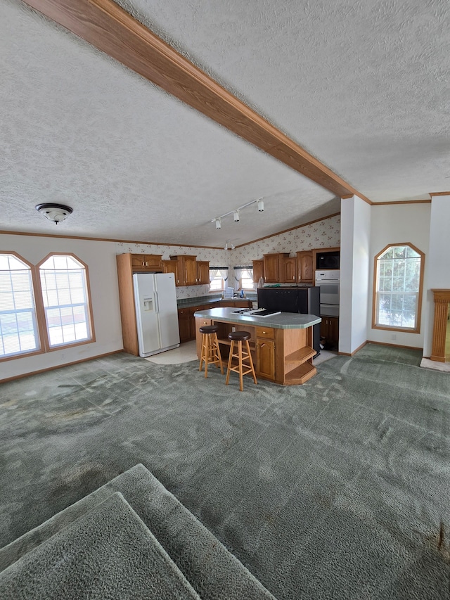 kitchen with white appliances, a center island, a breakfast bar area, and dark colored carpet