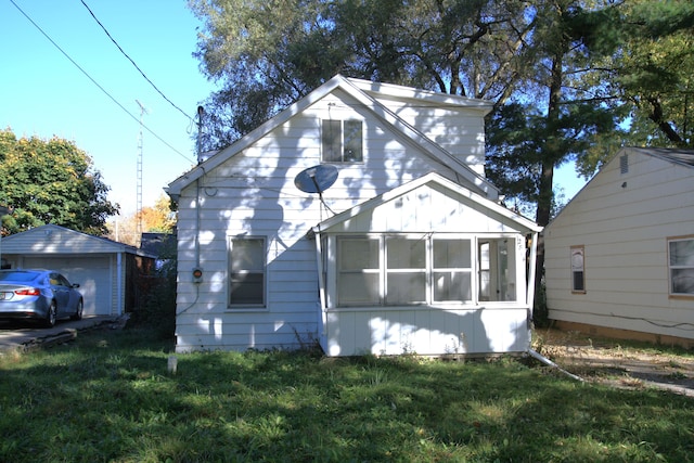 exterior space with an outbuilding, a sunroom, a garage, and a lawn