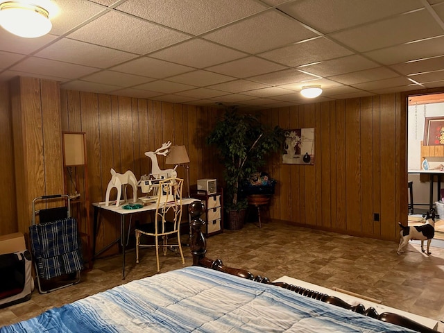 interior space with a paneled ceiling and wood walls