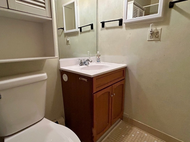 half bathroom with baseboards, vanity, toilet, and tile patterned floors