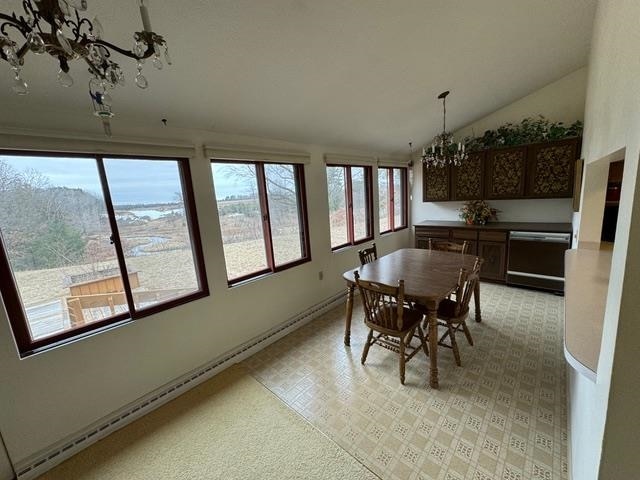 dining space featuring a baseboard heating unit, lofted ceiling, and an inviting chandelier