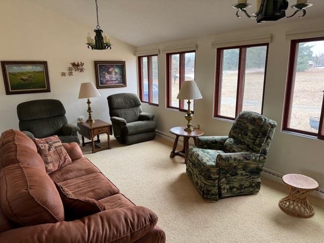 living room with plenty of natural light, carpet floors, a chandelier, and vaulted ceiling