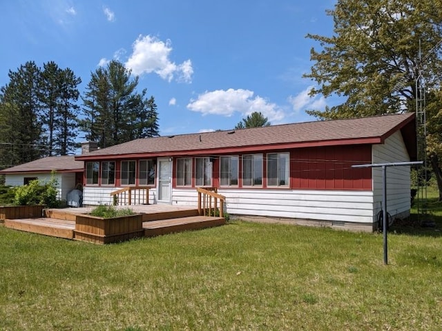 rear view of house featuring a yard, a wooden deck, and a sunroom