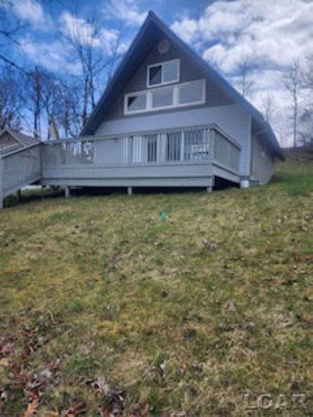 rear view of property featuring a yard and a wooden deck