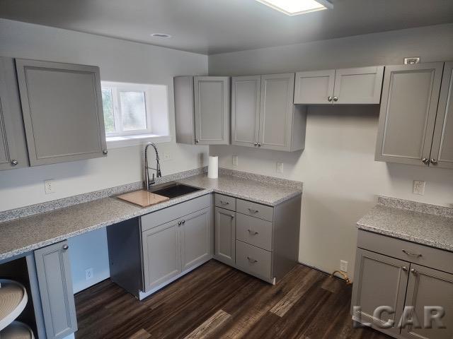 kitchen with dark wood-style floors, light countertops, a sink, and gray cabinetry