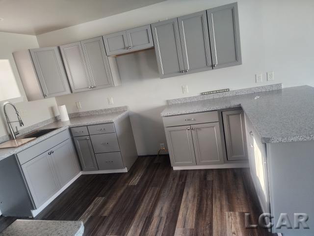 kitchen with dark wood-style floors, a sink, and gray cabinetry