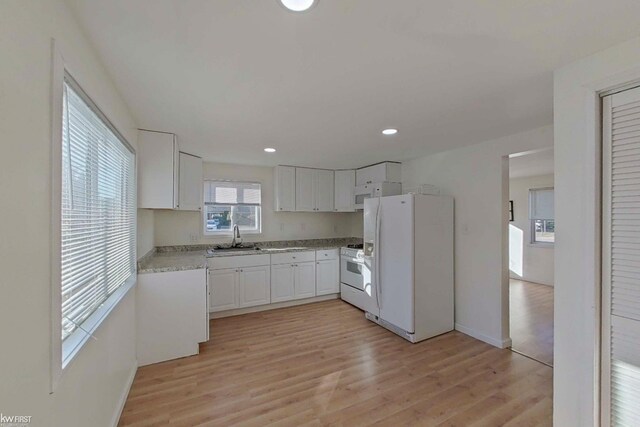 kitchen with light hardwood / wood-style flooring, white cabinets, white appliances, and sink