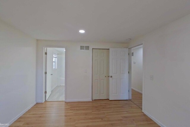 unfurnished bedroom with connected bathroom, a closet, and light hardwood / wood-style flooring