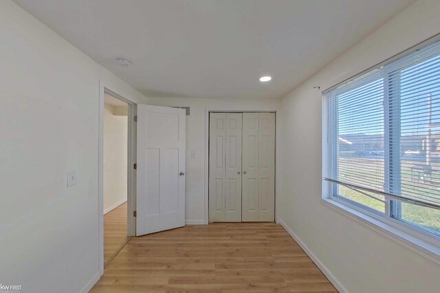 unfurnished bedroom with light wood-type flooring and multiple windows