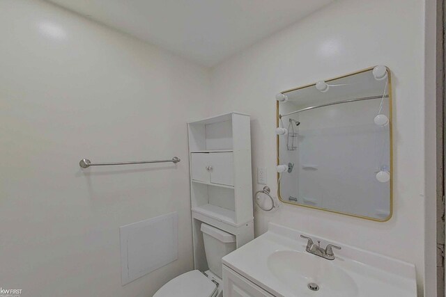 bathroom with toilet, a shower, and vanity