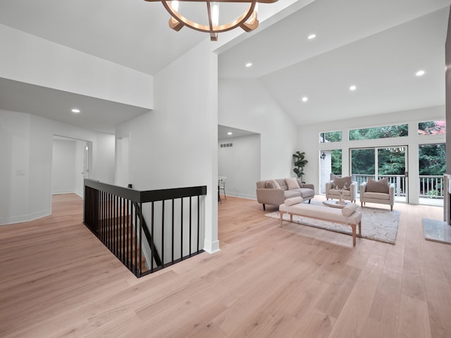 interior space with high vaulted ceiling, a chandelier, and light hardwood / wood-style flooring