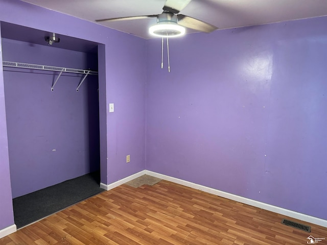 unfurnished bedroom featuring a closet, hardwood / wood-style flooring, and ceiling fan