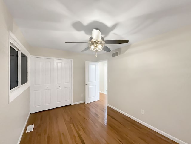 unfurnished bedroom featuring ceiling fan, a closet, and hardwood / wood-style flooring