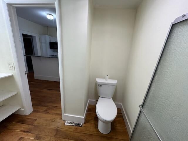 bathroom with hardwood / wood-style flooring and toilet