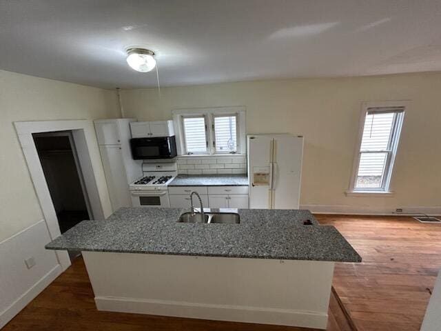 kitchen with white cabinets, white appliances, a healthy amount of sunlight, and dark stone countertops