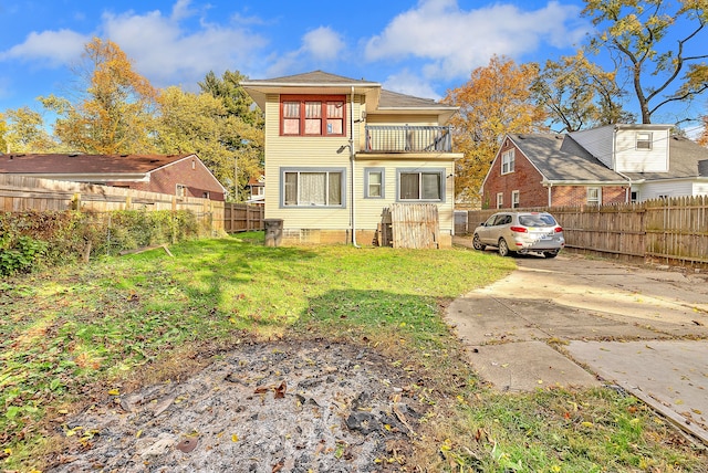 back of property featuring a balcony and a yard