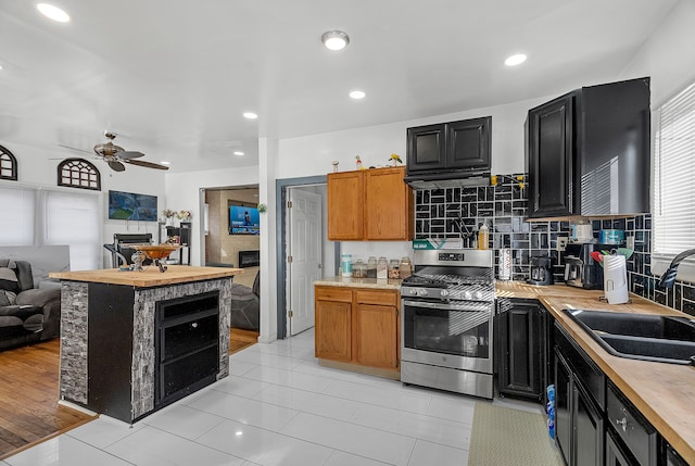 kitchen with tasteful backsplash, sink, ceiling fan, and stainless steel gas stove