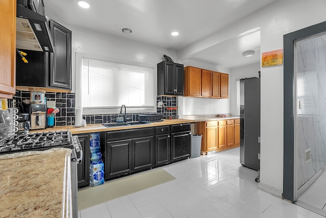 kitchen featuring tasteful backsplash, sink, exhaust hood, light tile patterned floors, and stainless steel appliances