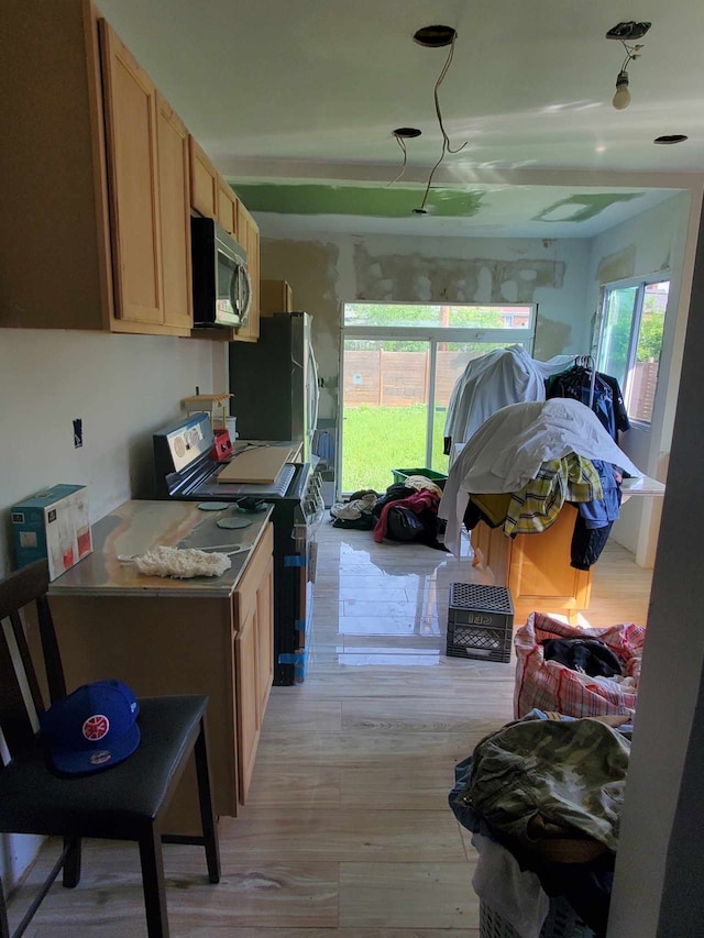 kitchen featuring plenty of natural light, light wood-type flooring, light brown cabinetry, and appliances with stainless steel finishes