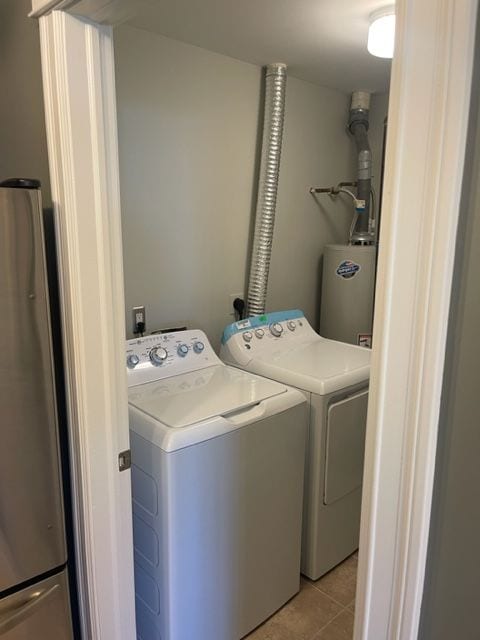 laundry area with washer and dryer, gas water heater, and light tile patterned floors