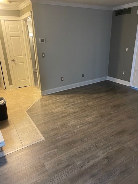 empty room with crown molding and wood-type flooring