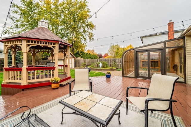 view of patio / terrace with a sunroom, a storage unit, a gazebo, and a wooden deck