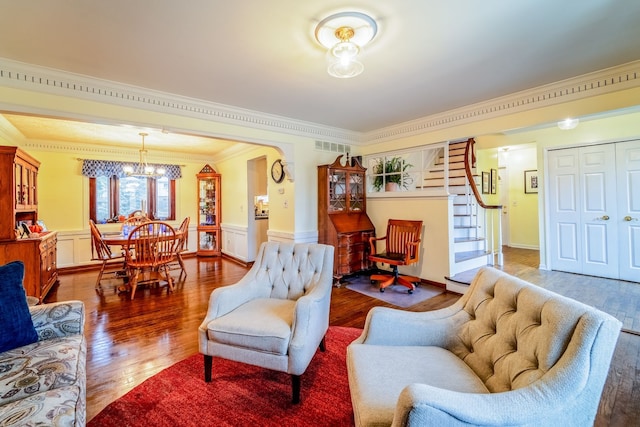 living room with dark wood-type flooring, ornamental molding, and a notable chandelier