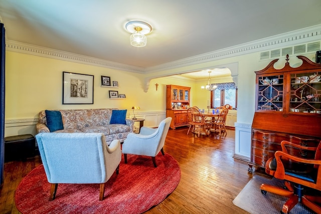 living room with a chandelier, wood-type flooring, and crown molding